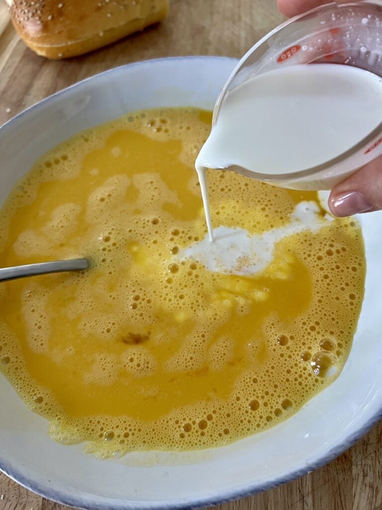 Adding milk to beaten eggs.