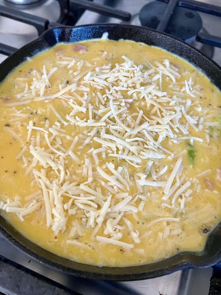 Eggs topped with grated cheese in pan ready to go into the oven.