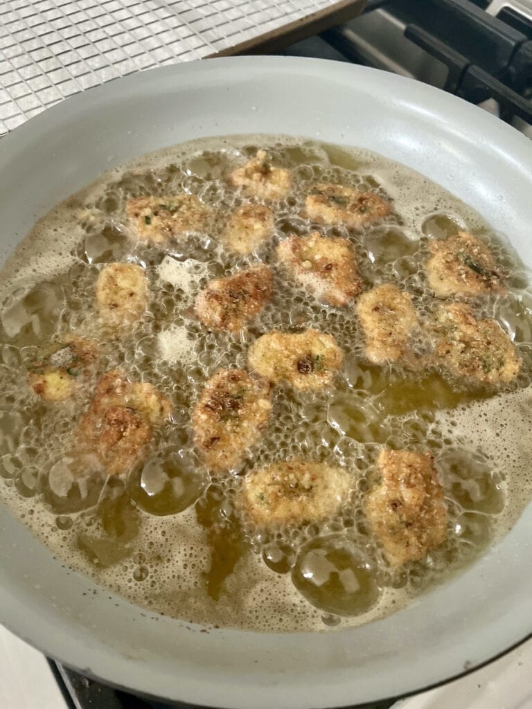 Frying artichoke hearts in oil in a large pan.
