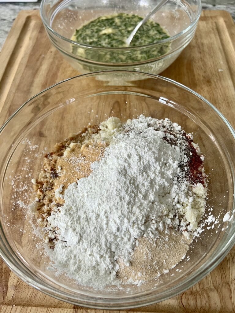 Seasoned breadcrumb ingredients combined in a glass bowl with egg mixture in background.