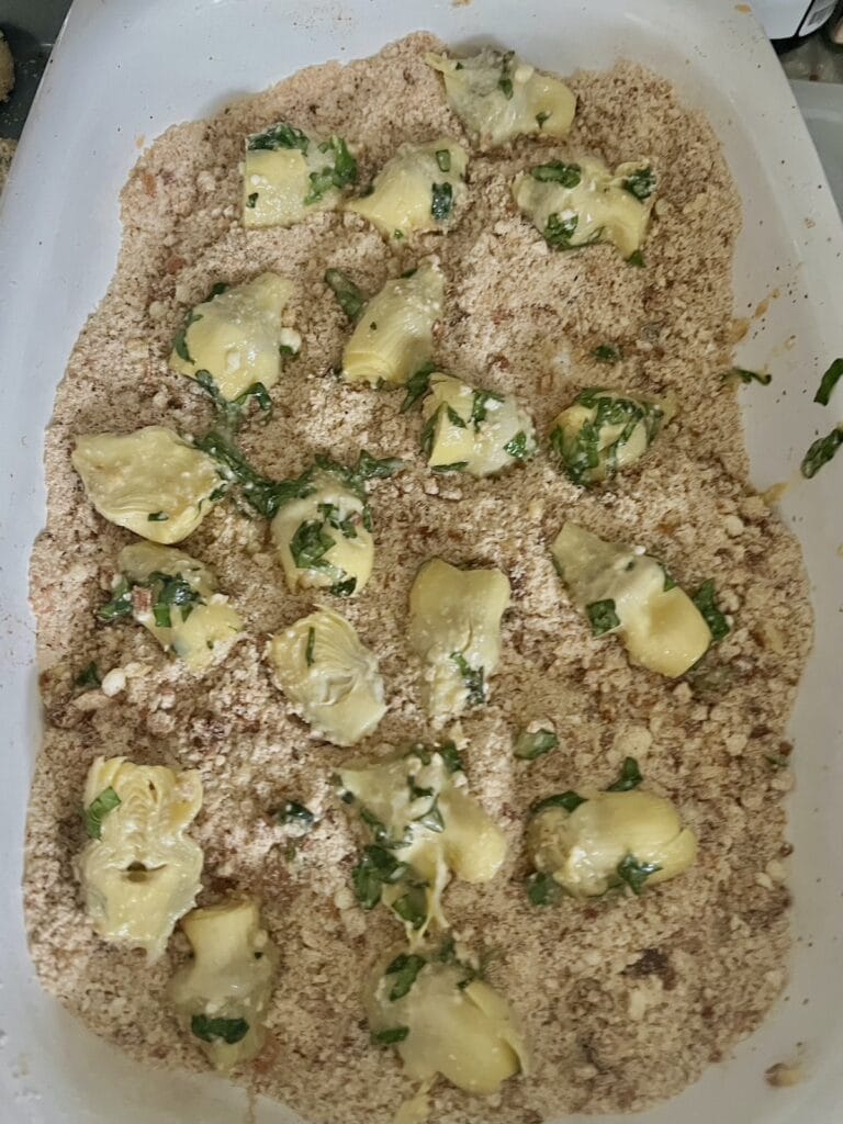 Artichoke hearts being breaded in seasoned breadcrumbs.
