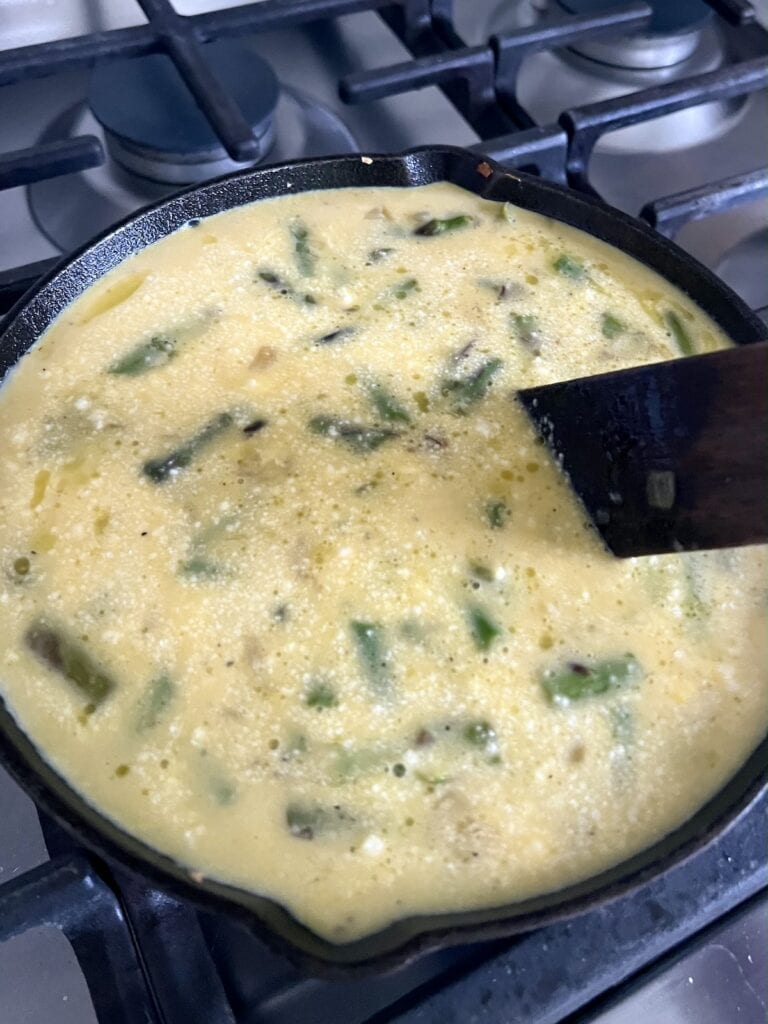 Spreading out the ingrdients in pan with a wooden utensil.