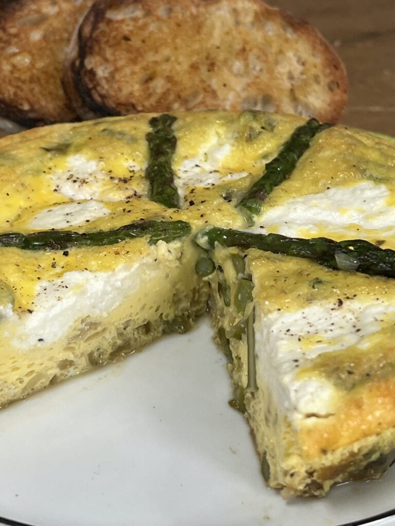 Cut-open, side view of the beautiful inside of asparagus and egg frittata.