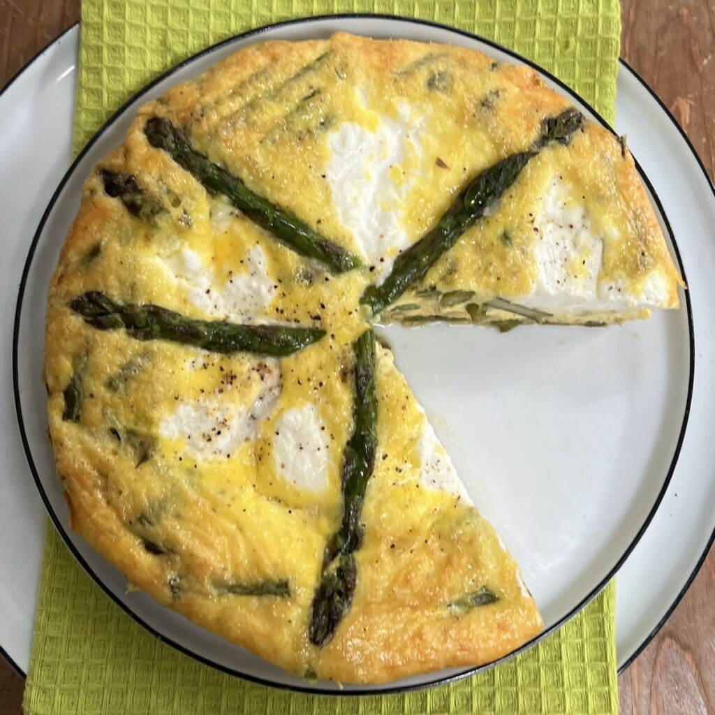 Overhead view of Italian asparagus frittata turned out onto a dish with one sliced removed.