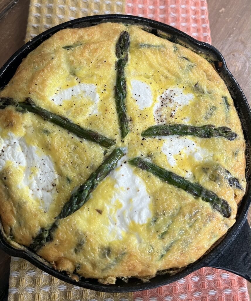 Finished Italian Asparagus Frittata in cast iron pan over decorative towel.