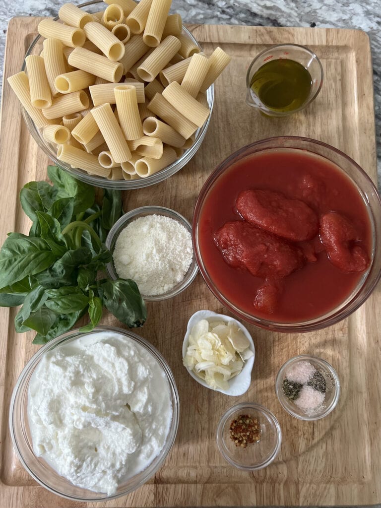 All ingredients for tomato ricotta pasta on cutting board.