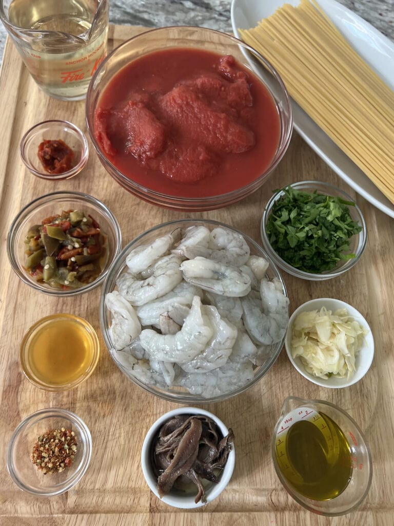 All spicy shrimp arrabbiata pasta recipe ingredients on cutting board.