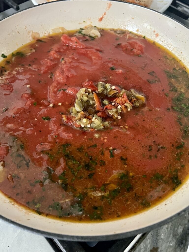 Tomatoes and hot cherry peppers added to pan to make the shrimp arrabbiata pasta sauce.