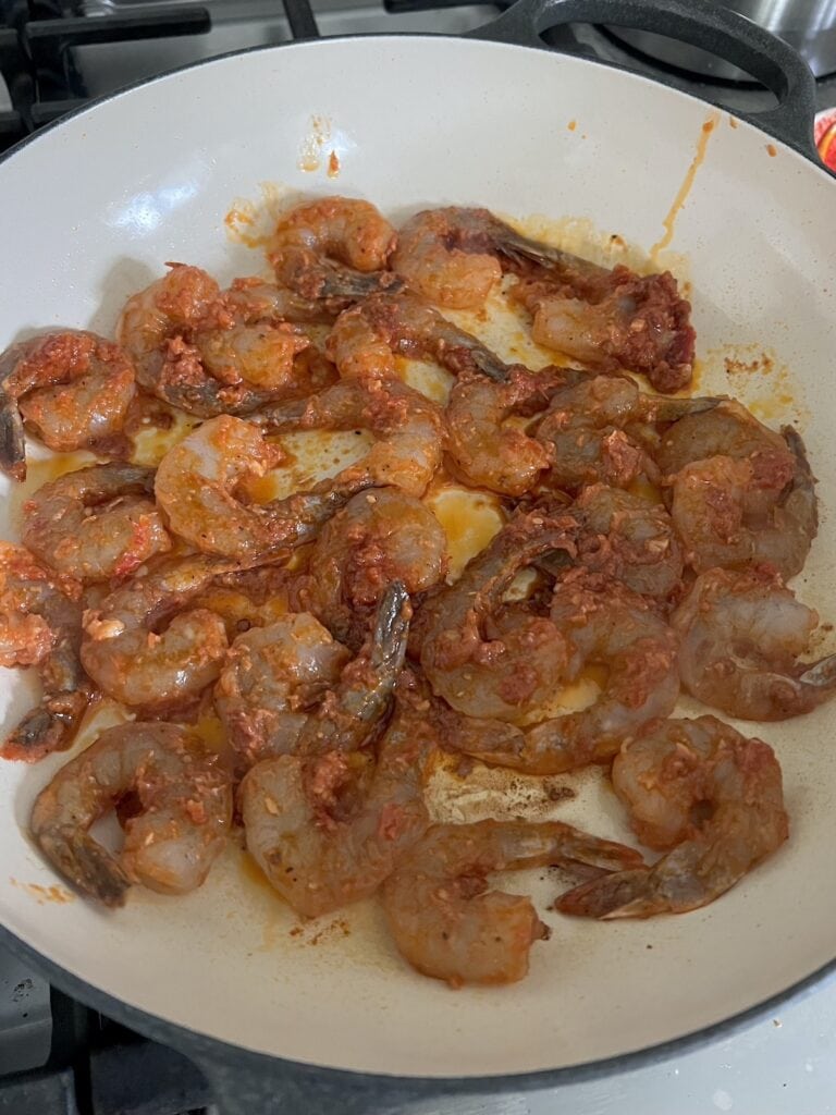 Searing spicy tomato shrimp in pan.
