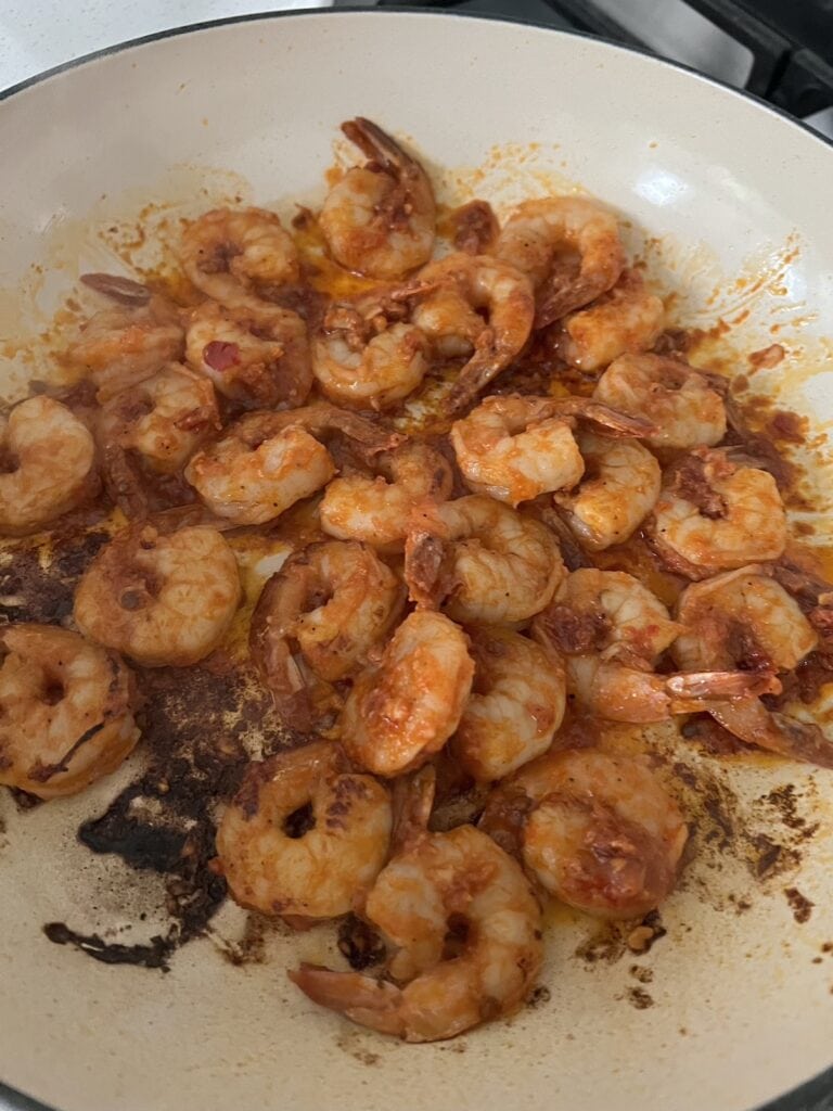 Searing spicy tomato shrimp in pan.