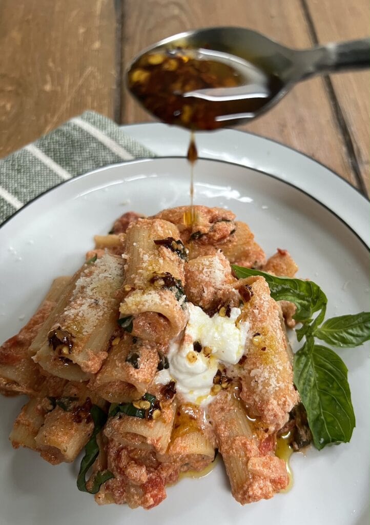 Drizzling spicy pepper oil over tomato and ricotta pasta.