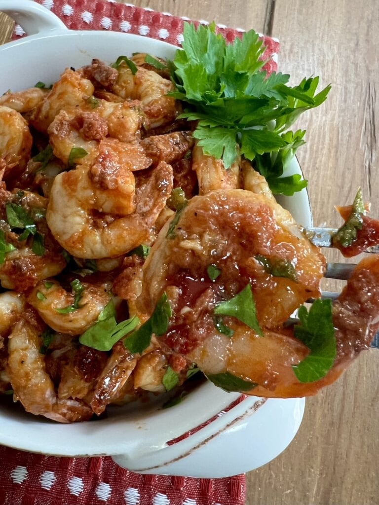 Close up of one piece of spicy shrimp fra diavolo recipe with a plate of them in the background.