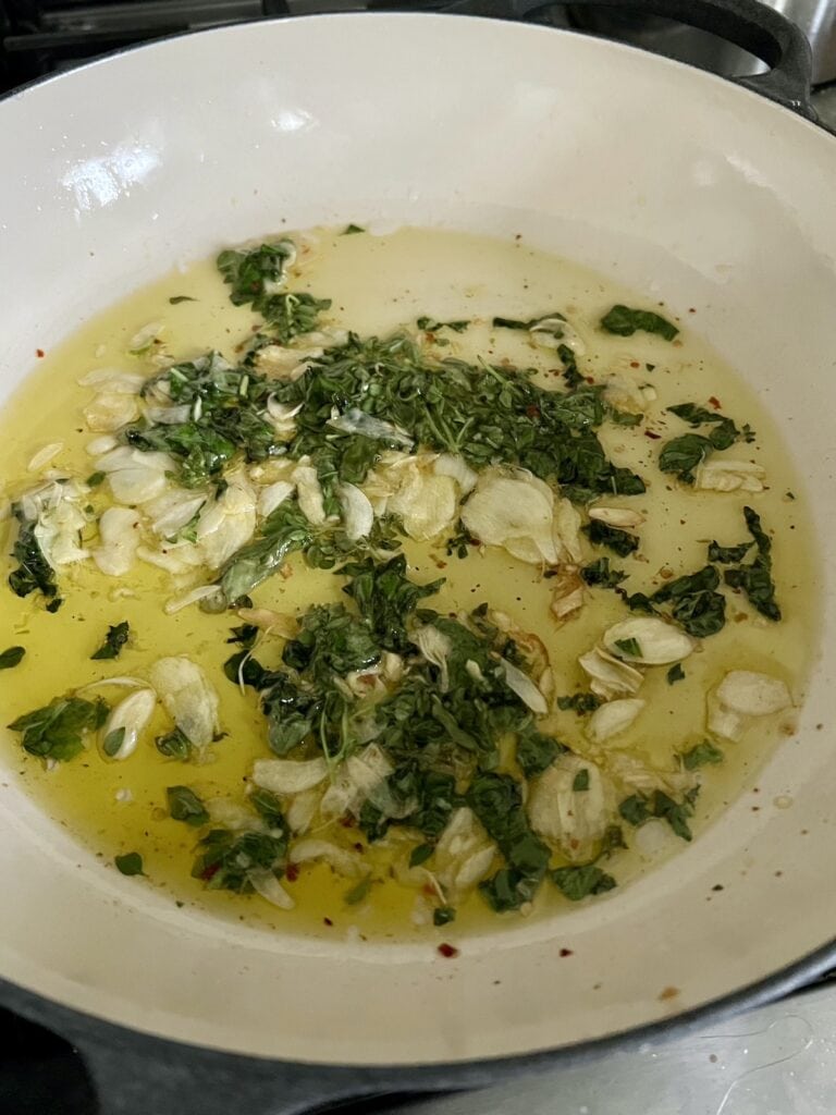 Sautéing garlic and basil in olive oil in pan.