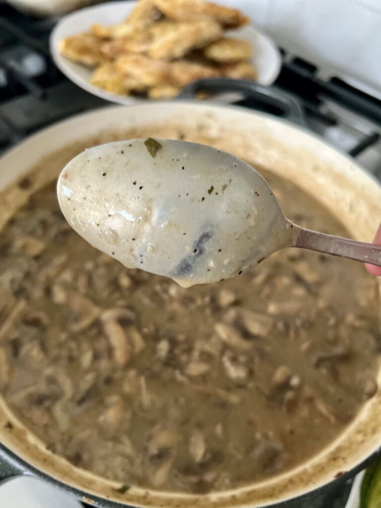 Checking the thickness of the chicken francese sauce with the back of a spoon.