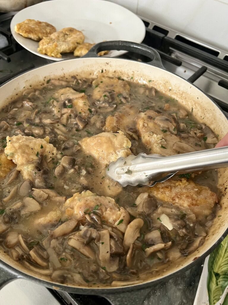 Adding cooked chicken pieces back to pan in sauc.