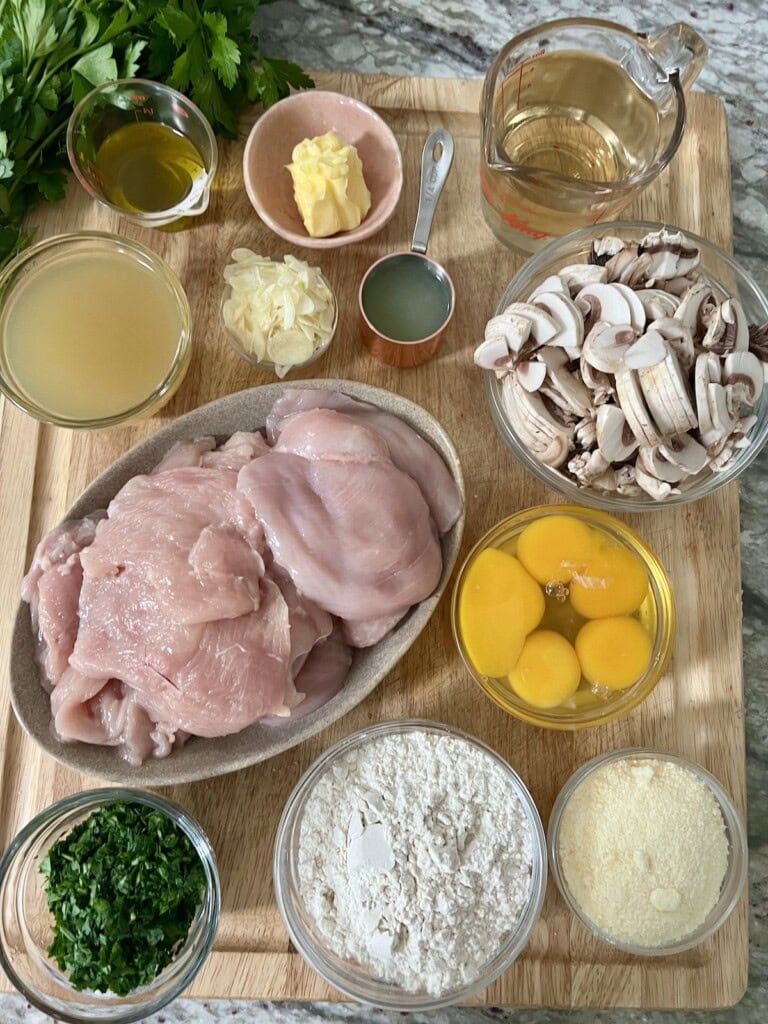 Prepped ingredients for italian chicken francaise with mushrooms on cutting board.