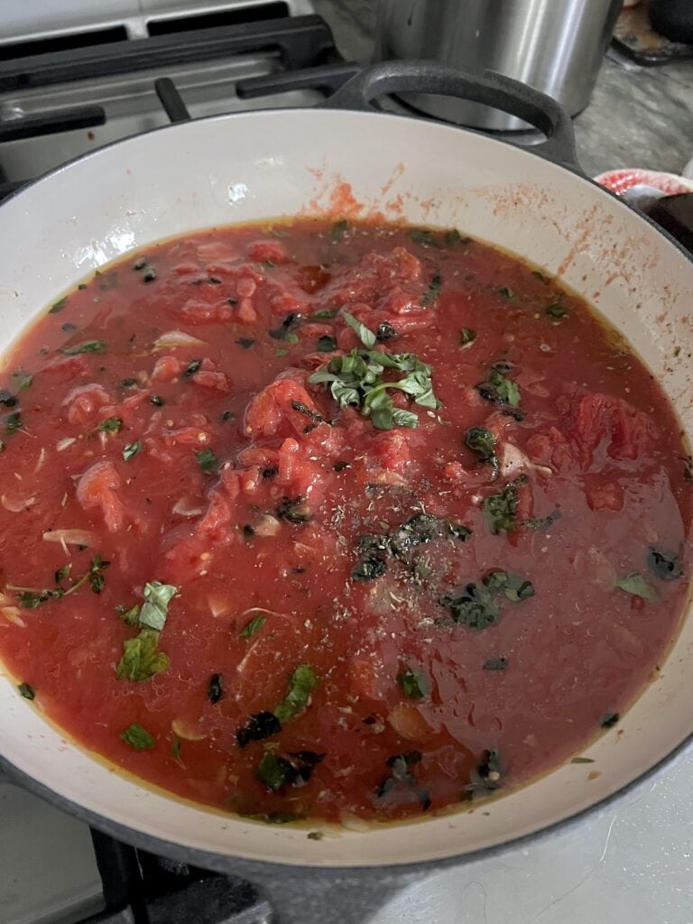 Tomatoes, salt and black pepper added to garlic and oil in pan.