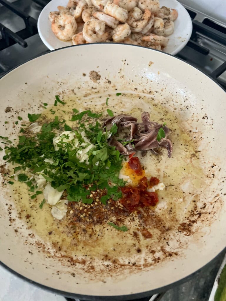 Sautéing garlic, anchovy, red pepper flakes, calabrian chile flakes and parsley in olive oil in same pan shrimp were cooked in.