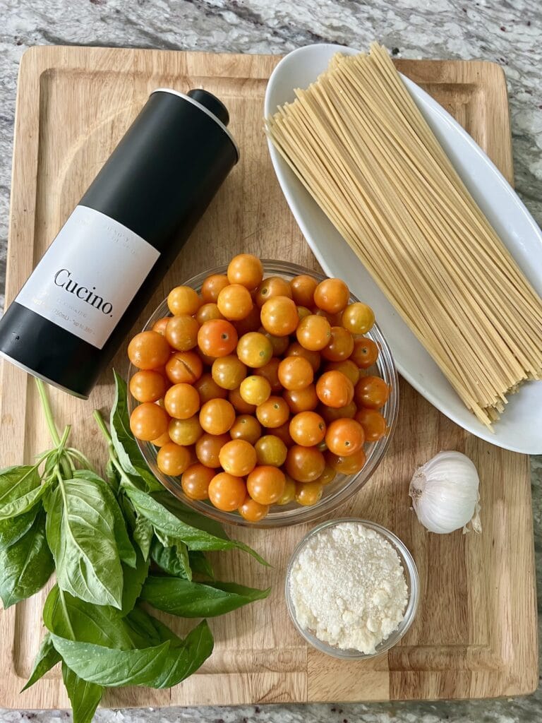 All ingredients for sungold tomato pasta on cutting board.