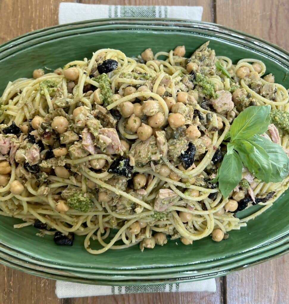 Tuna Pesto pasta in green serving platter with basil sprig garnish.