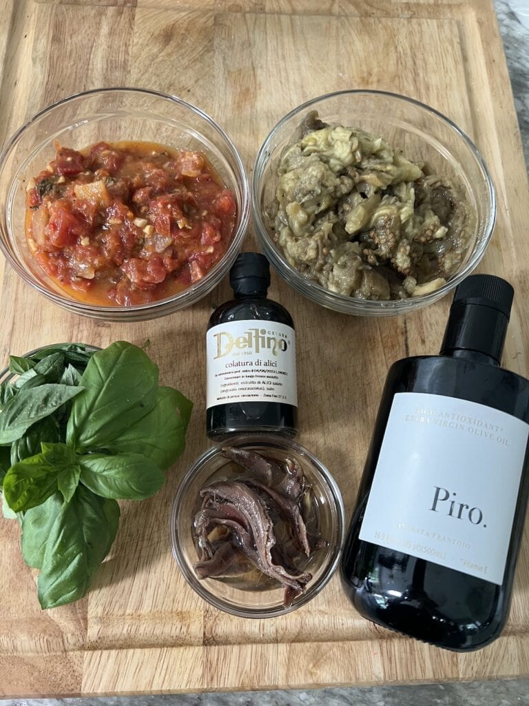 Roasted veggies with olive oil, anchovies, basil and colatura di alici on cutting board.