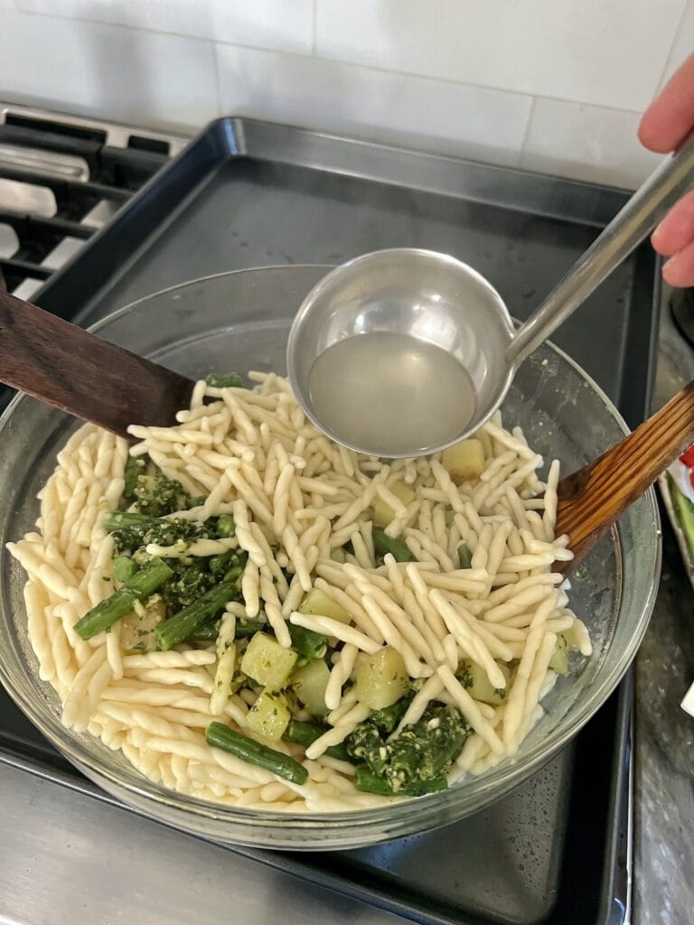 Adding some pasta water to the trofie al pesto genovese.