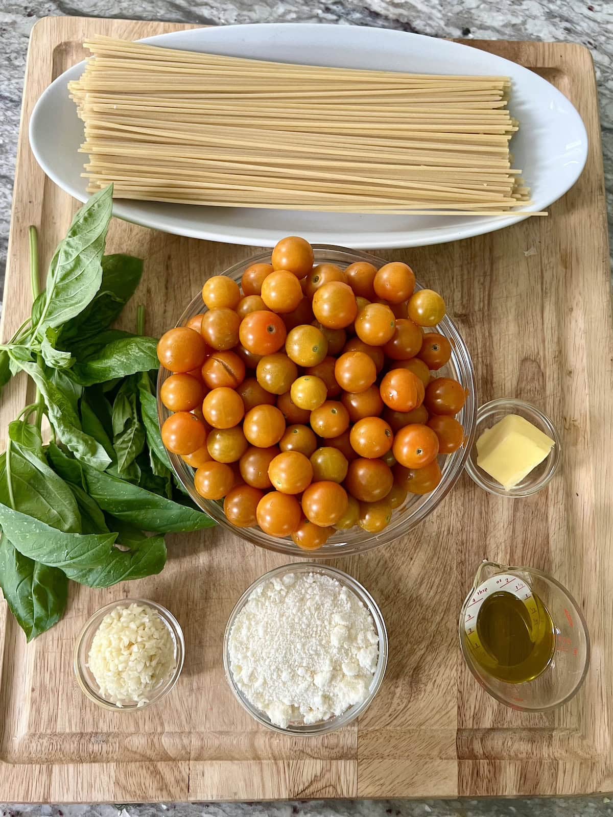 All prepped ingredients for pasta with sun gold tomatoes recipe on cutting board.