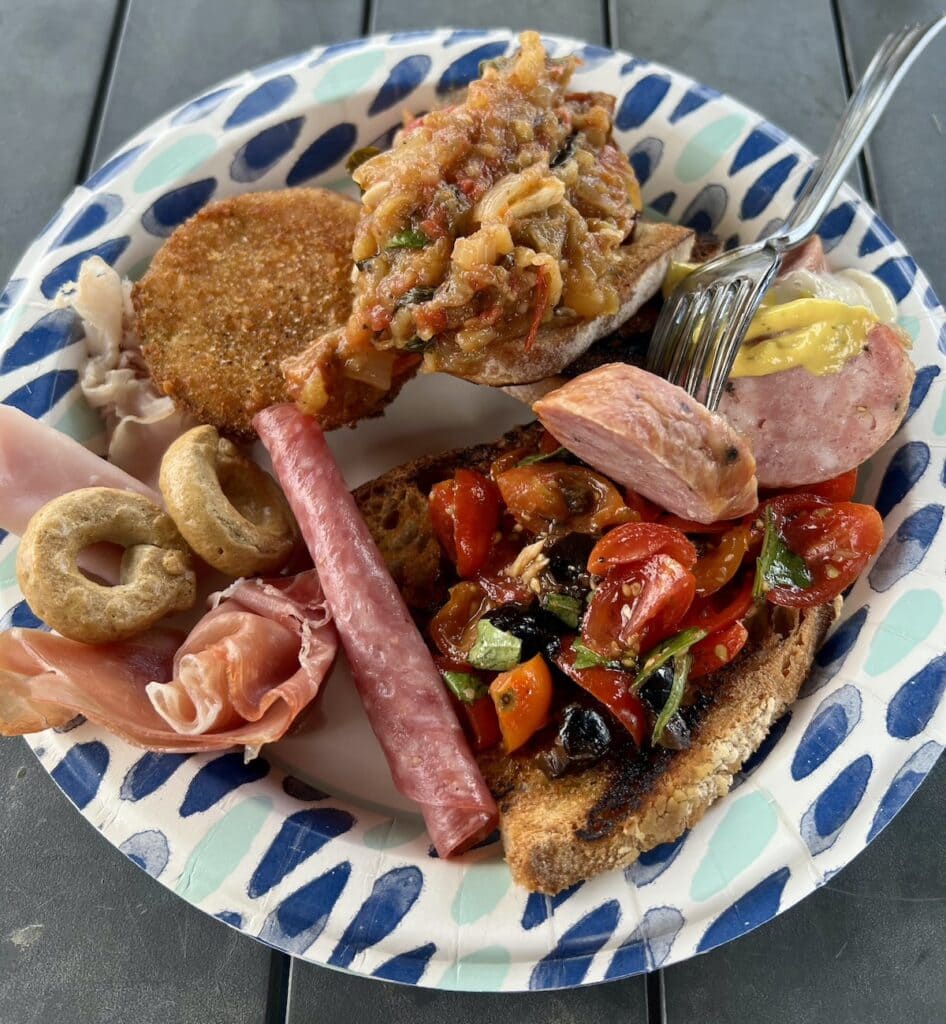 Plate of assorted antipasti including a scoop of roasted eggplant tomato dip or spread.
