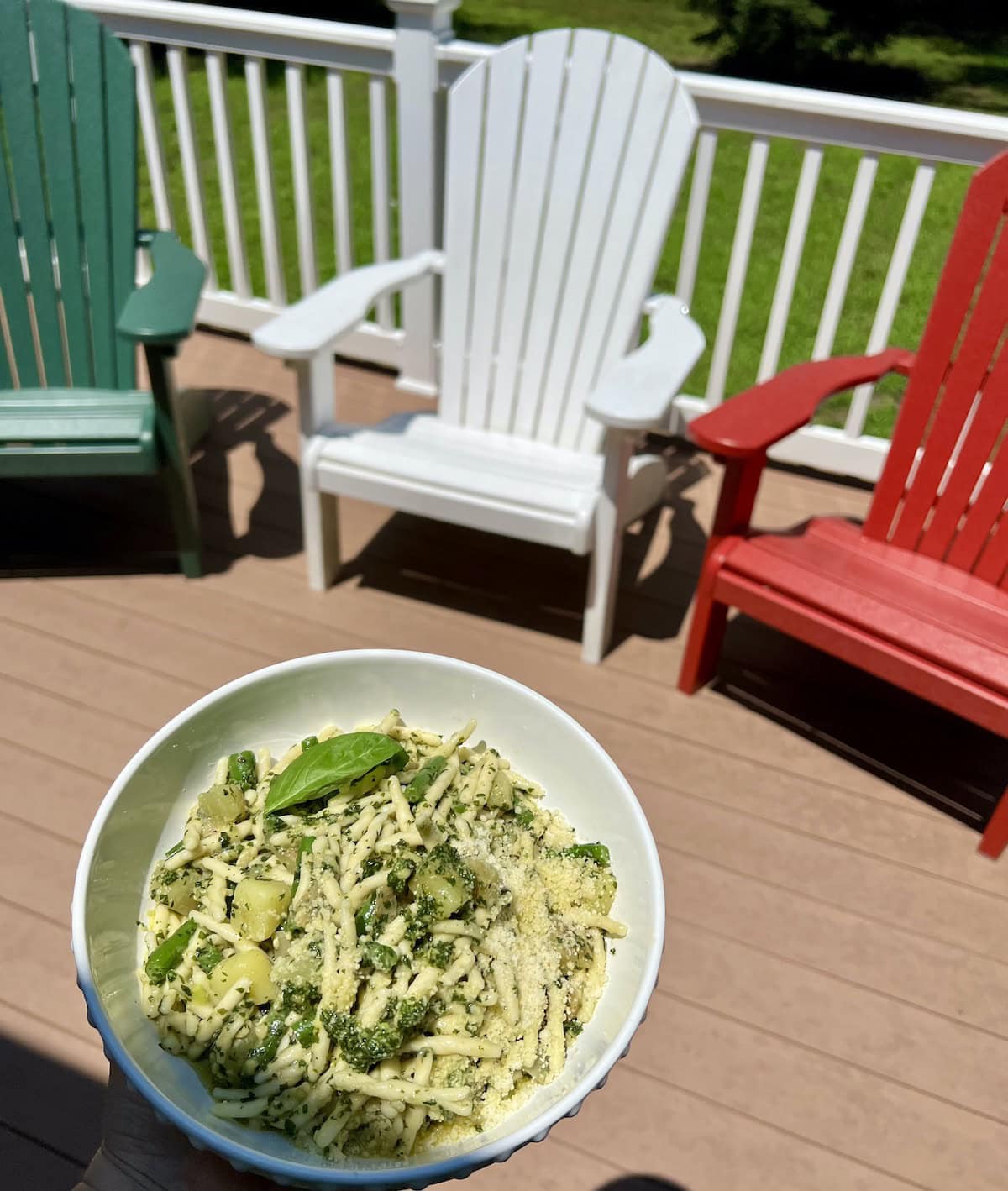 Bowl of Pasta with Pesto Green Beans and Potatoes with deck chairs in background.