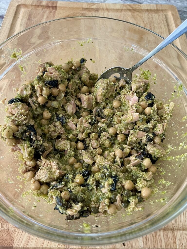 Sauce ingredients in glass bowl being mixed by spoon.