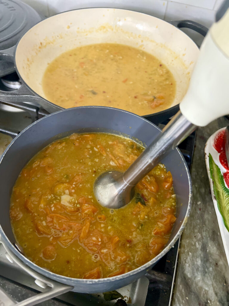 Pureeing the yellow cherry tomato pasta sauce with a hand-held immersion blender.