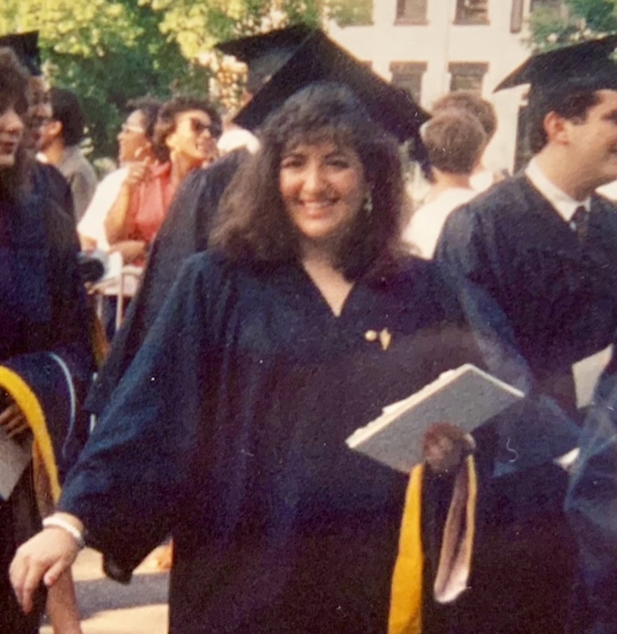 Michele at college graduation in graduation cap and gown.