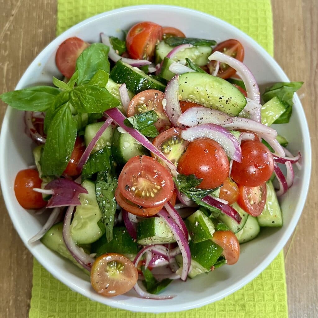 Cucumber tomatoa salad in white serving bowl.