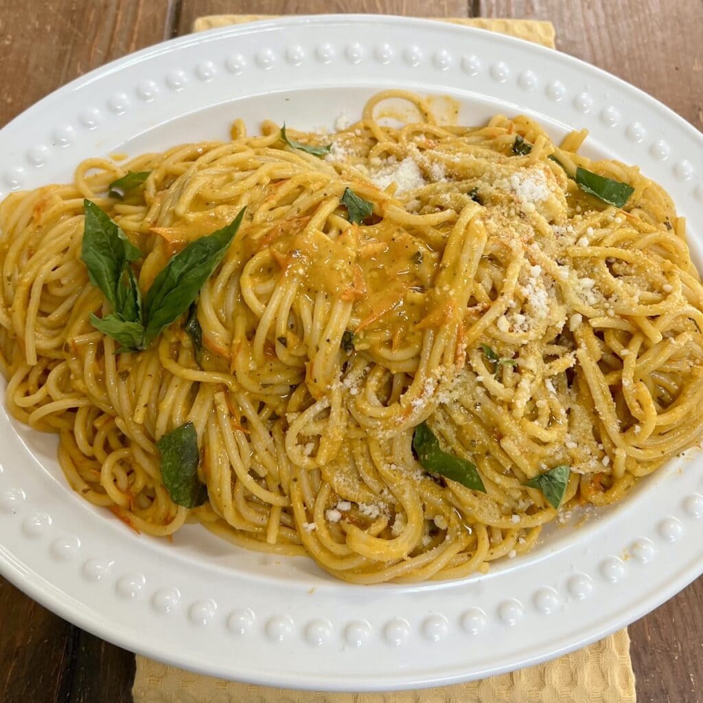 Sun gold pasta with basil garnish on white serving platter.