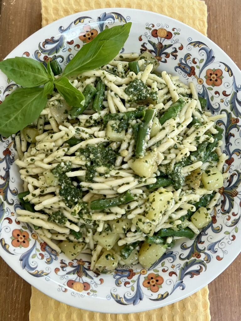 Trofie al pesto genovese in decorative bowl with basil sprig garnish.