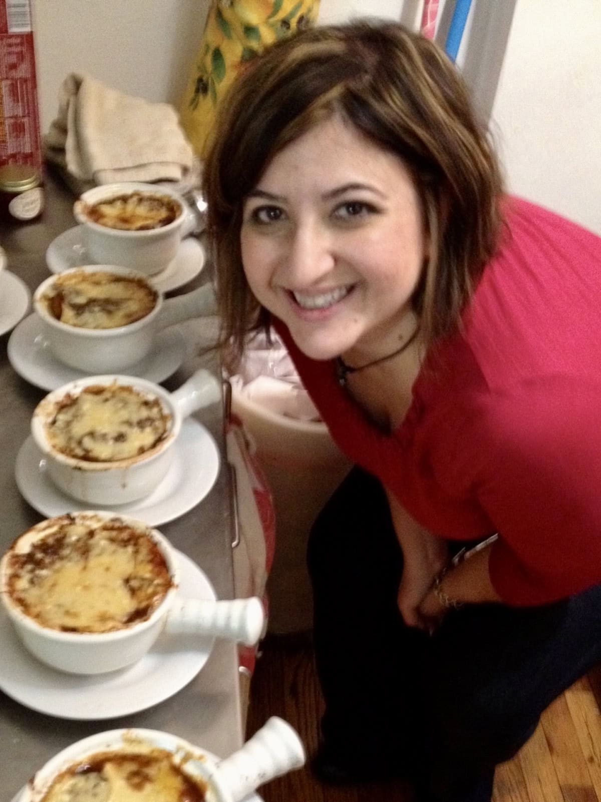 Michele leaning over table that has 4 bowls of soup.