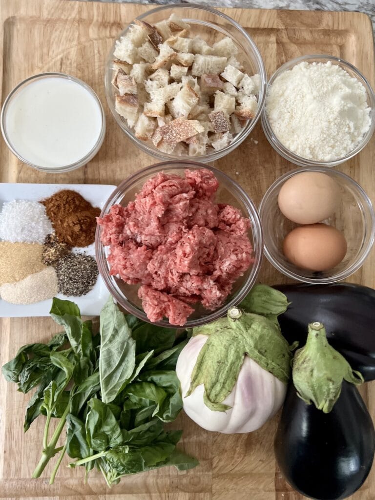 All ingredients for beef meatballs with eggplant on cutting board.