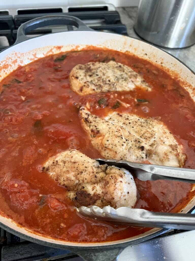 Adding seared chicken breasts back to sauce in pan for the Easy Chicken Pomodoro recipe.