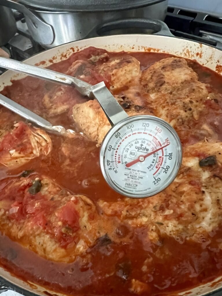 Checking the internal temperature of the chicken with a stem thermometer.