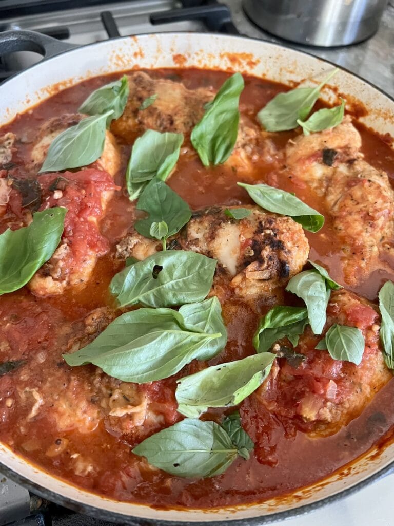Adding basil leaves to the finished pomodoro chicken.