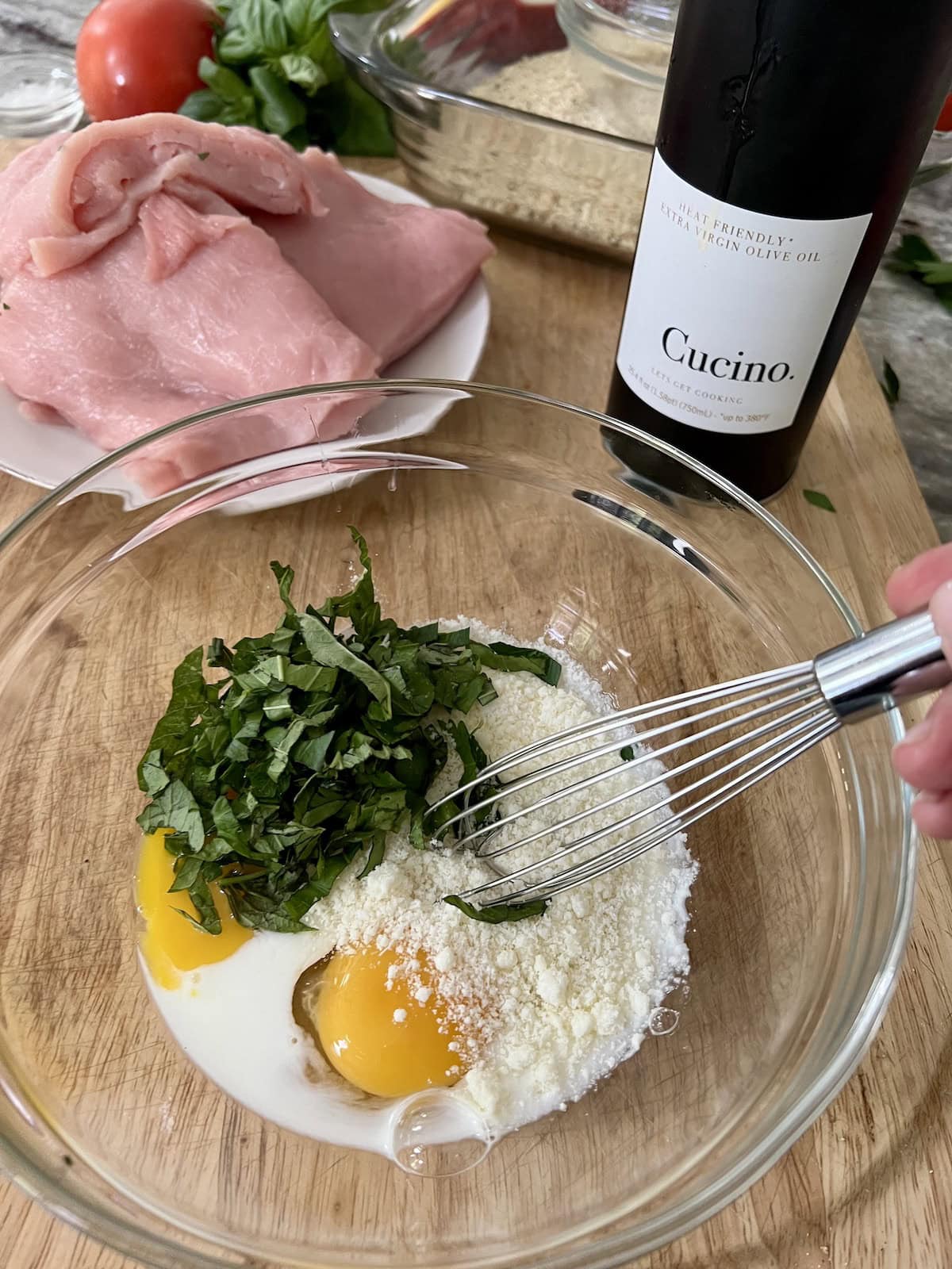 Whisking eggs, milk, cheese and fresh herbs together in bowl.