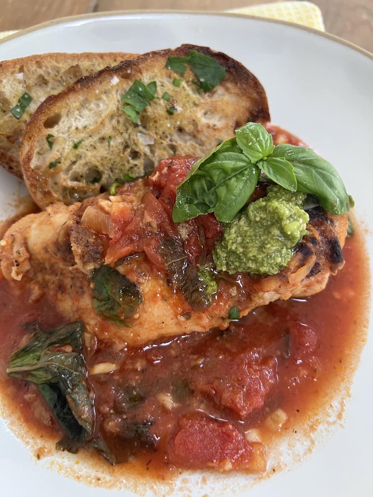 Easy Pomodoro Chicken on a white dinner plate with toasted bread and basil garnish.