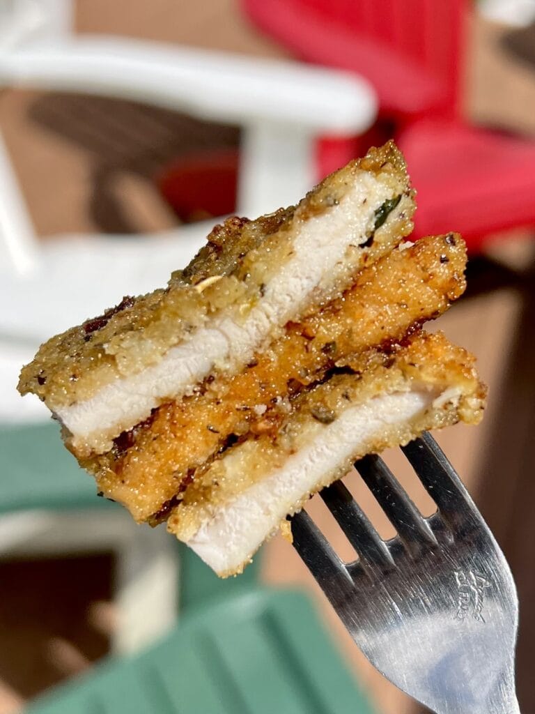 Close up of two pieces of breaded pork cutlets on fork.