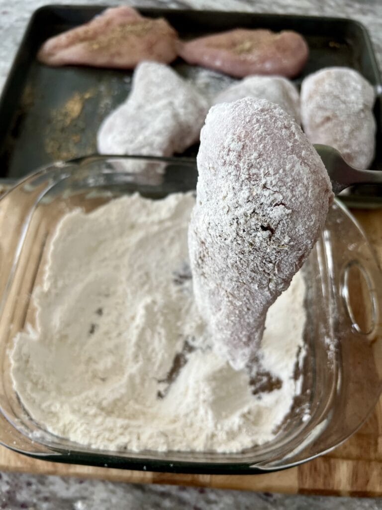 Flour-coated chicken breast on fork.