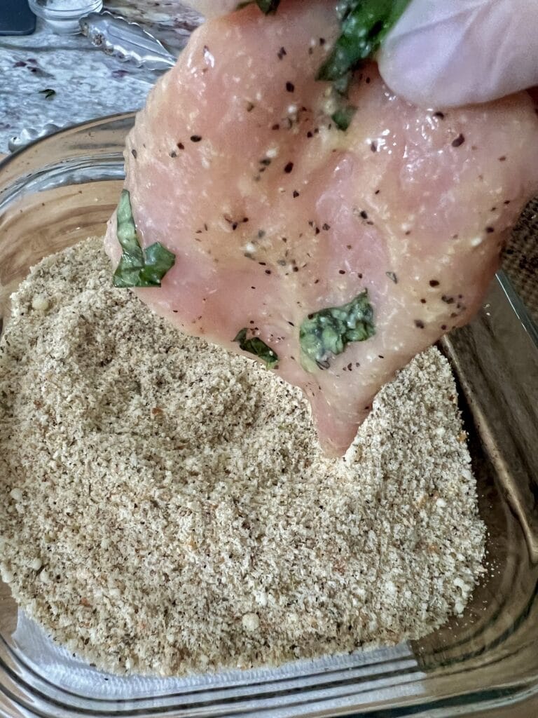 Breading the thin piece of meat in seasoned breadcrumbs.