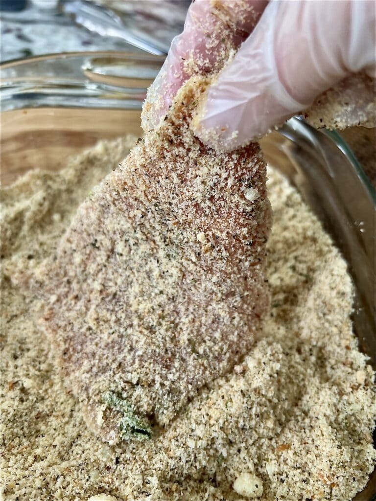 Breading the thin piece of meat in seasoned breadcrumbs.