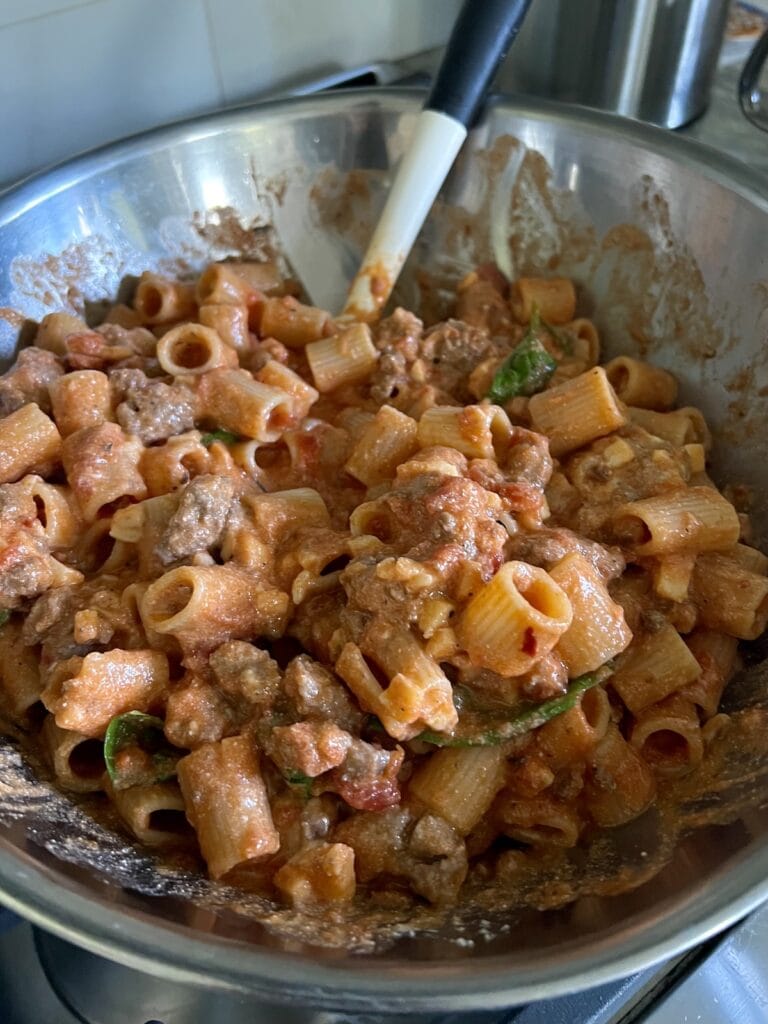 All ingredients for rigatoni and meat sauce mixed together in a large bowl, with spatula.