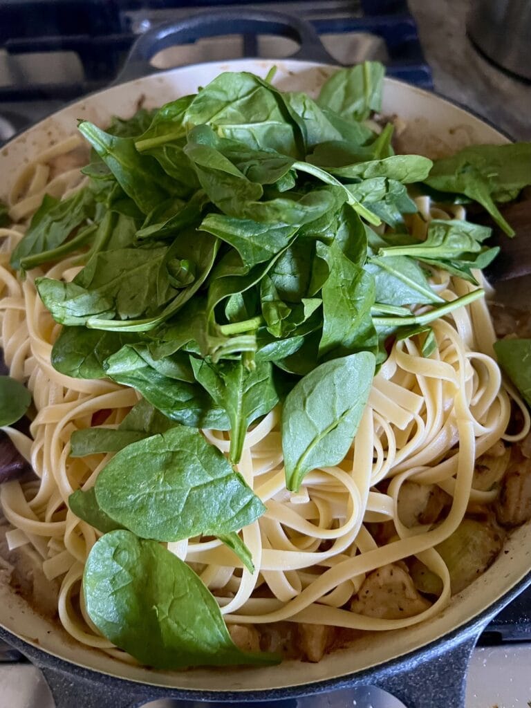 Baby spinach just added to pan with cooked pasta.