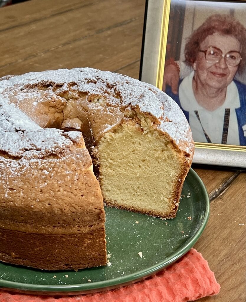 Old fashioned sour cream pound cake on green plate with picture of my mom in the background.