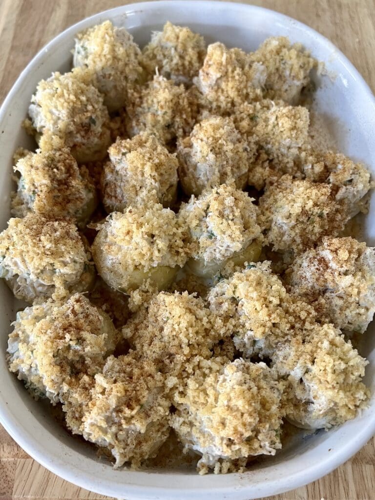 Breadcrumb topped stuffed artichoke bottom sin baking dish ready for the oven.